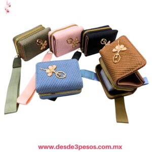 Mini monedero texturizado con cierre y correa de mano, decorado con dije al centro, en colores surtidos. 10 x 7.5 cm. H-1062